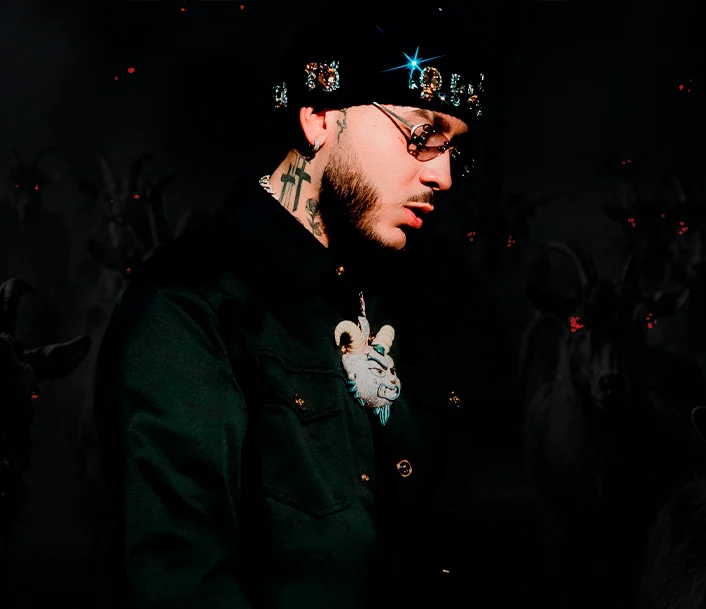 Kris R de perfil, con gorro de piedras brillantes, gafas y camisa oscura.