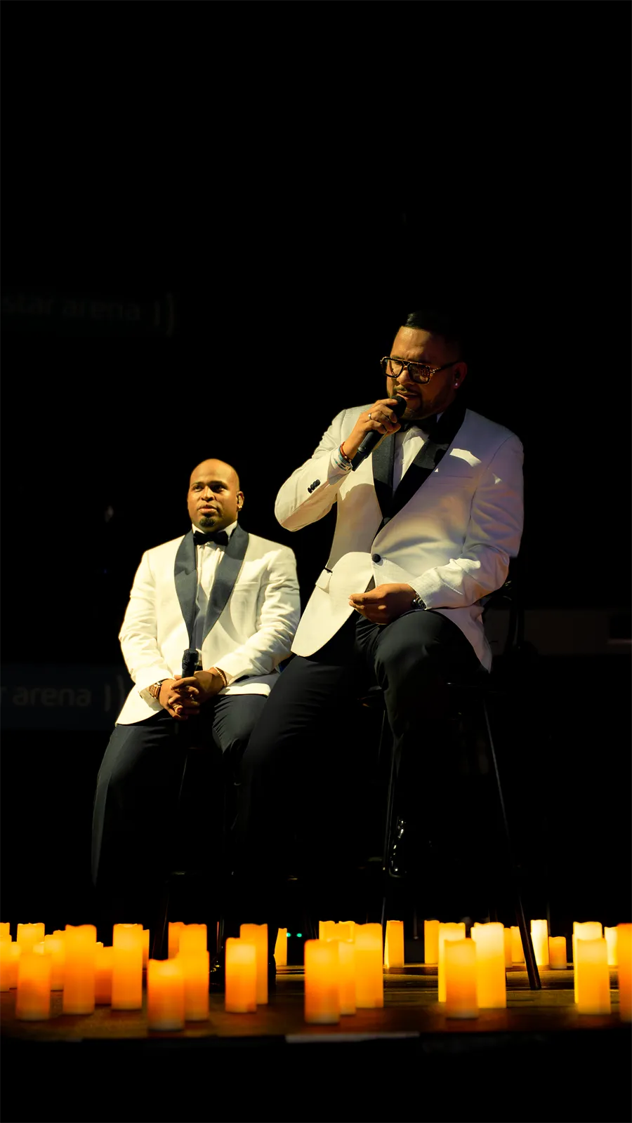 Dos cantantes en el escenario, sobre una fila de velas.