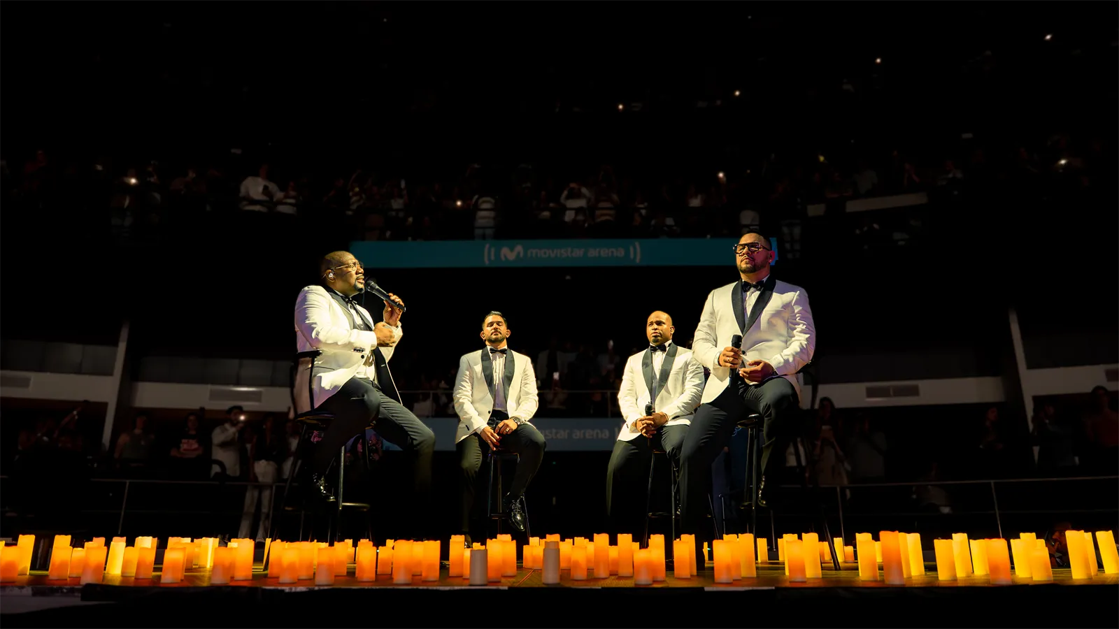 Cuatro cantantes en el escenario frente a la hilera de velas.