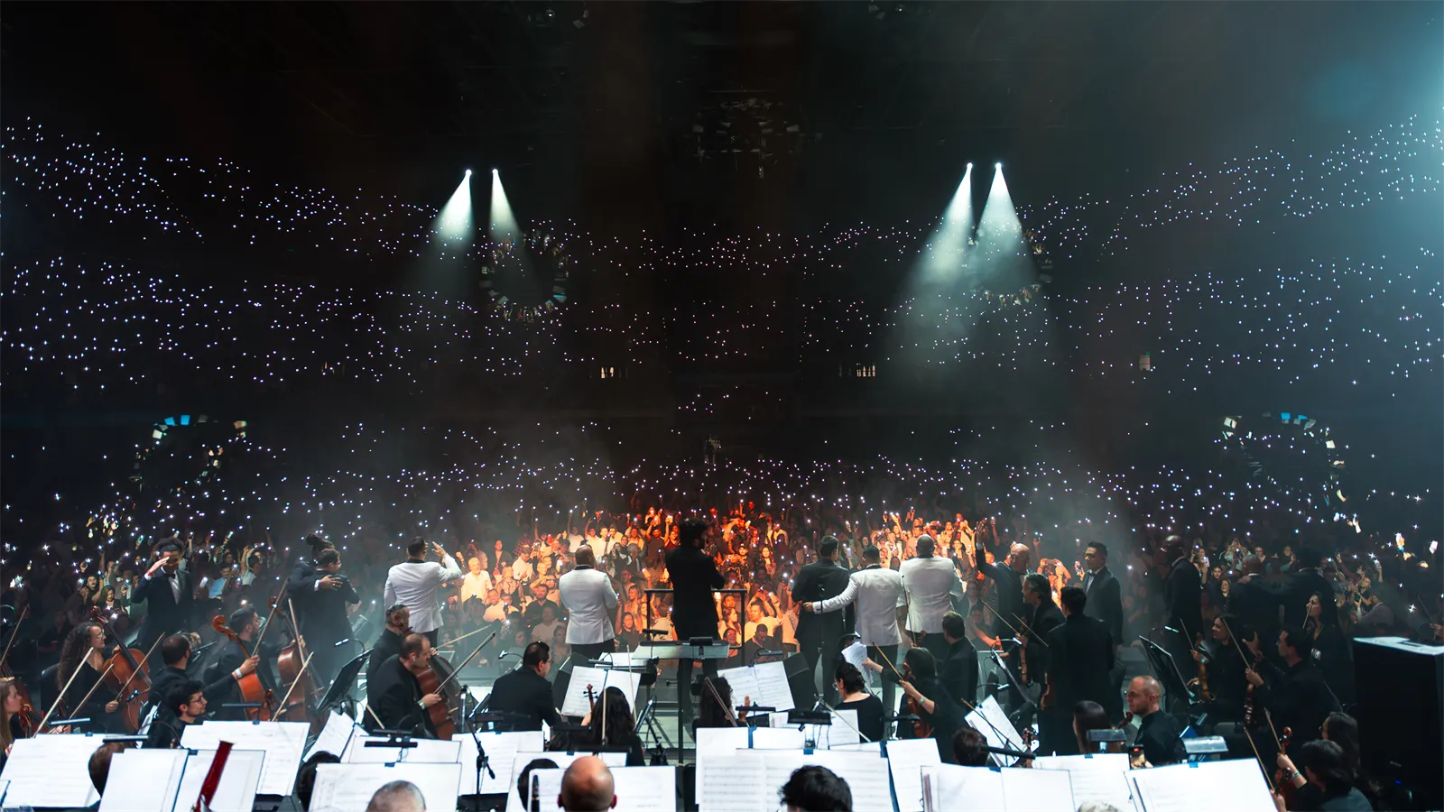 El escenario desde atrás de la orquesta, con el público iluminado.